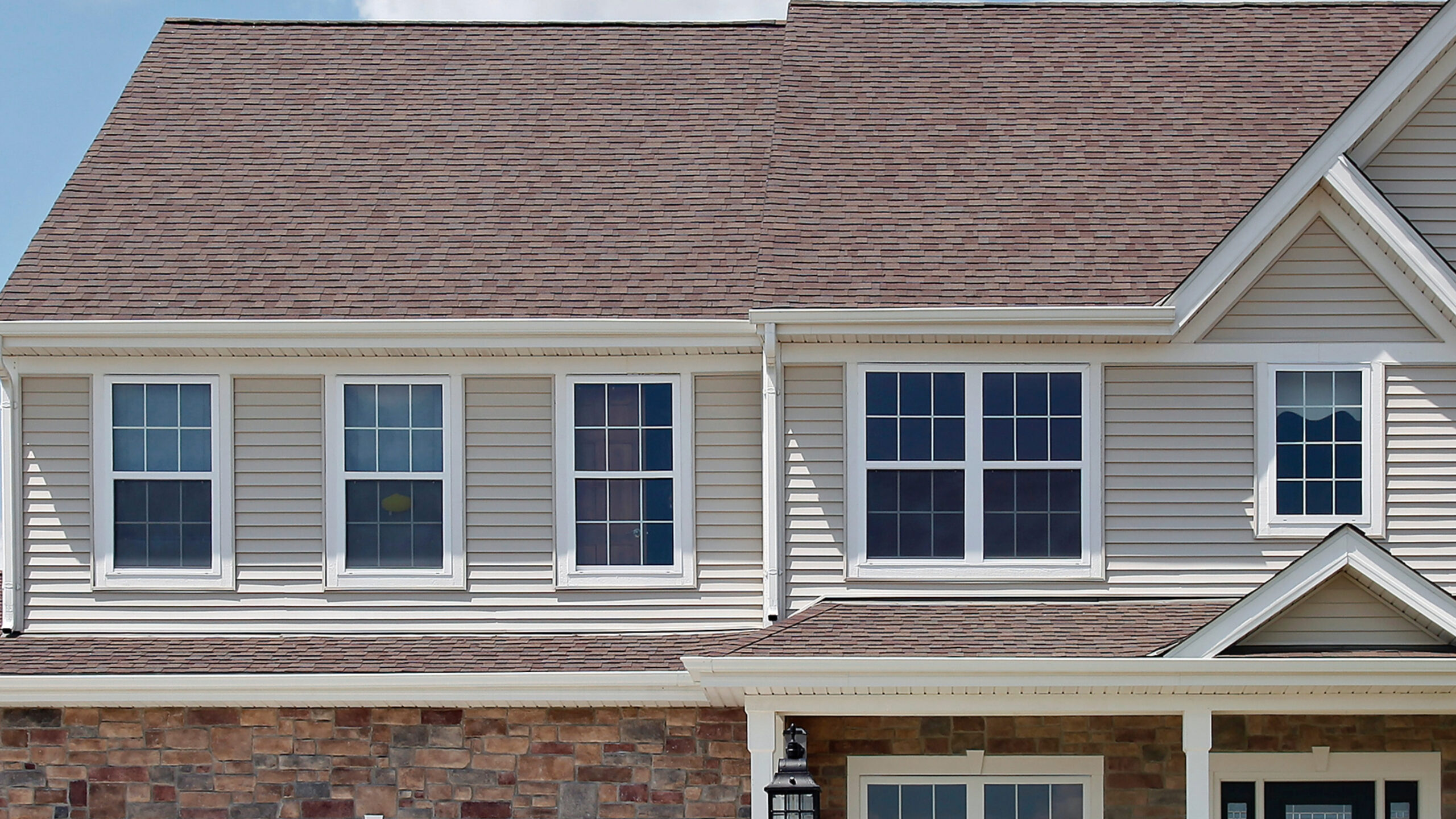 Three white trim windows in a home with beige siding