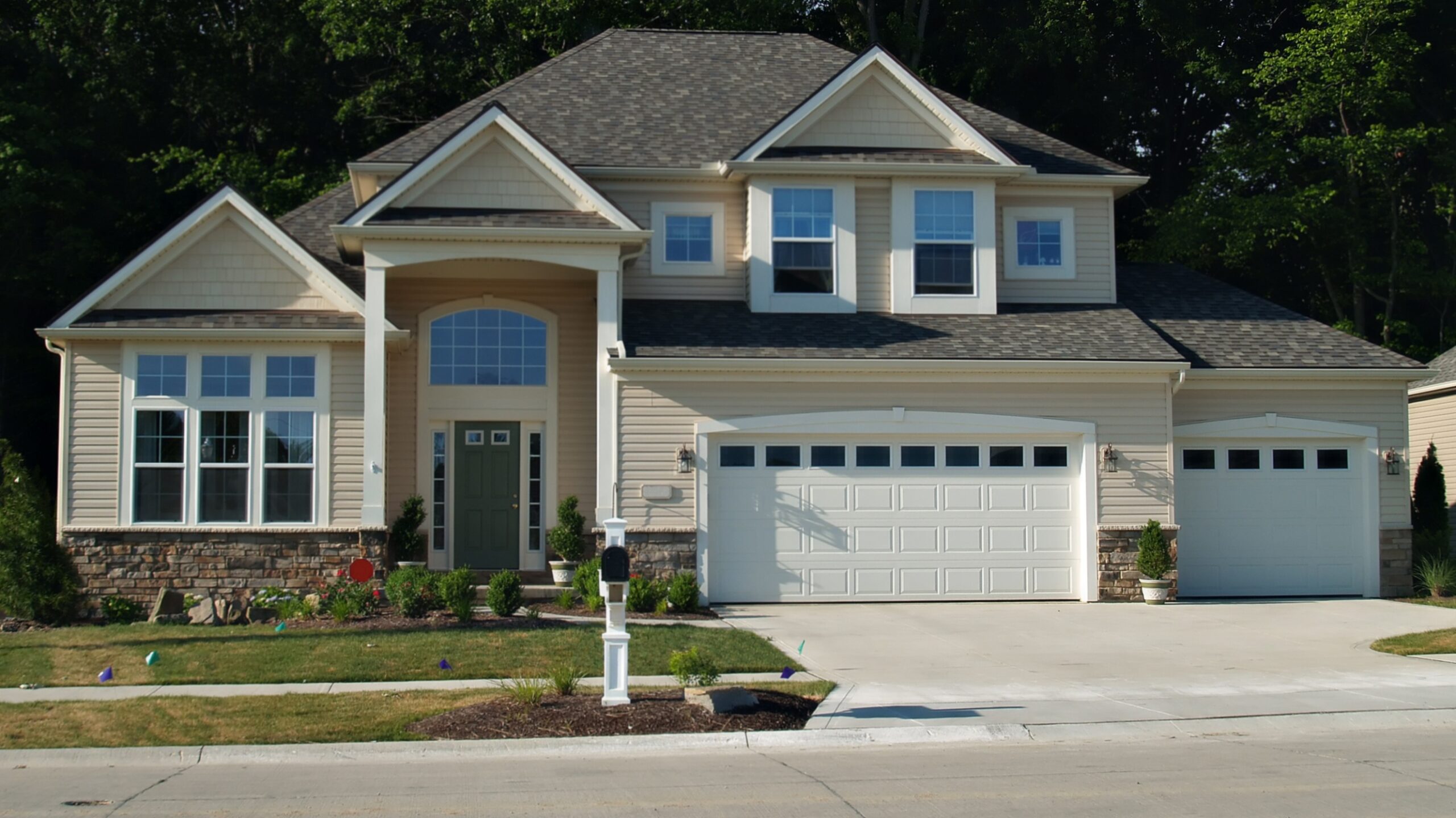 A home with beige siding, white trim, and a gray asphalt shingle roof