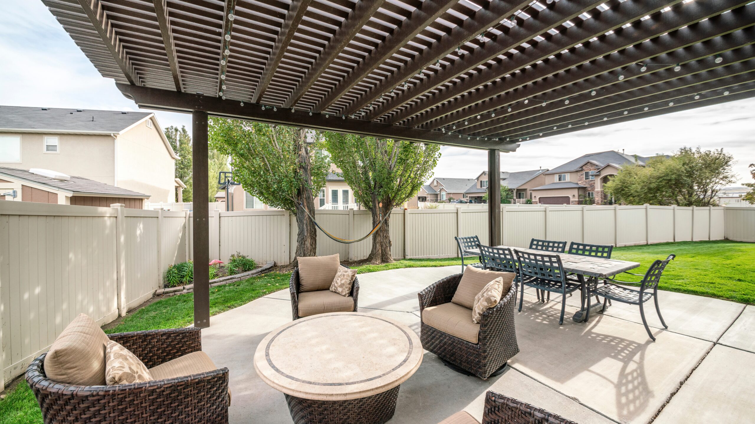 A brown pergola installed over a patio with a full outdoor dining set