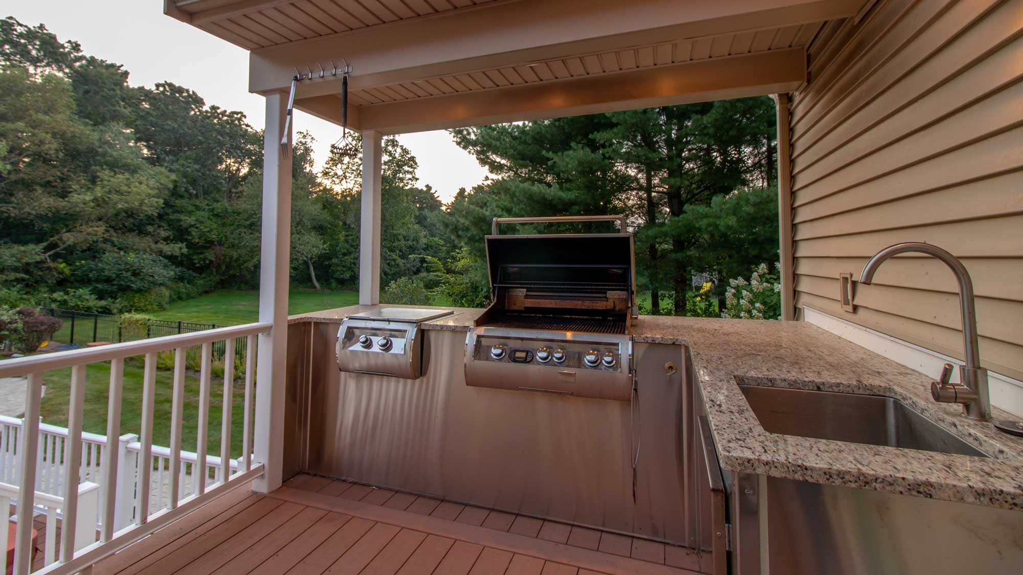 An outdoor kitchen with a sink, grill, and cooktop
