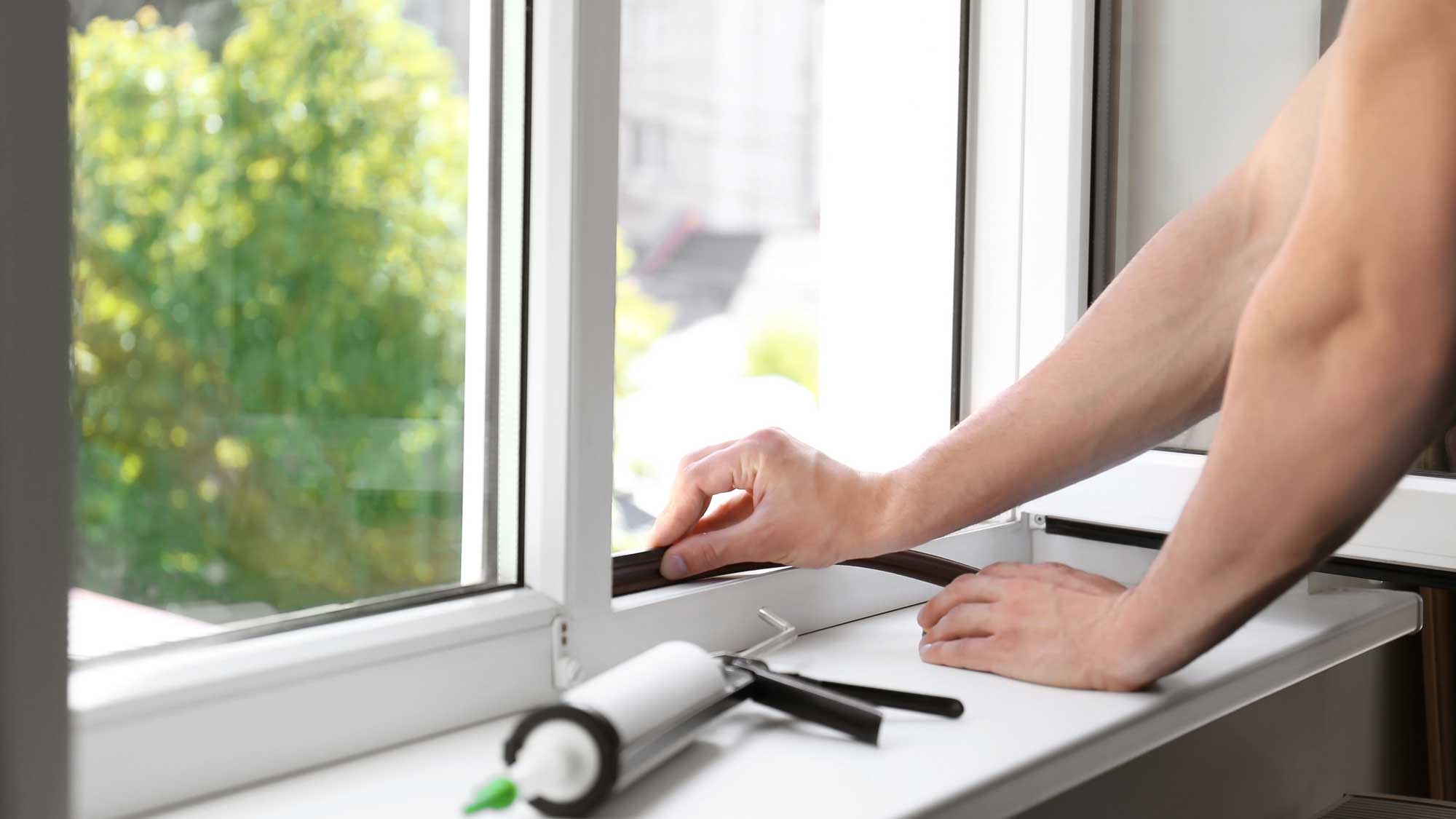 An installer placing weatherstripping in a replacement window