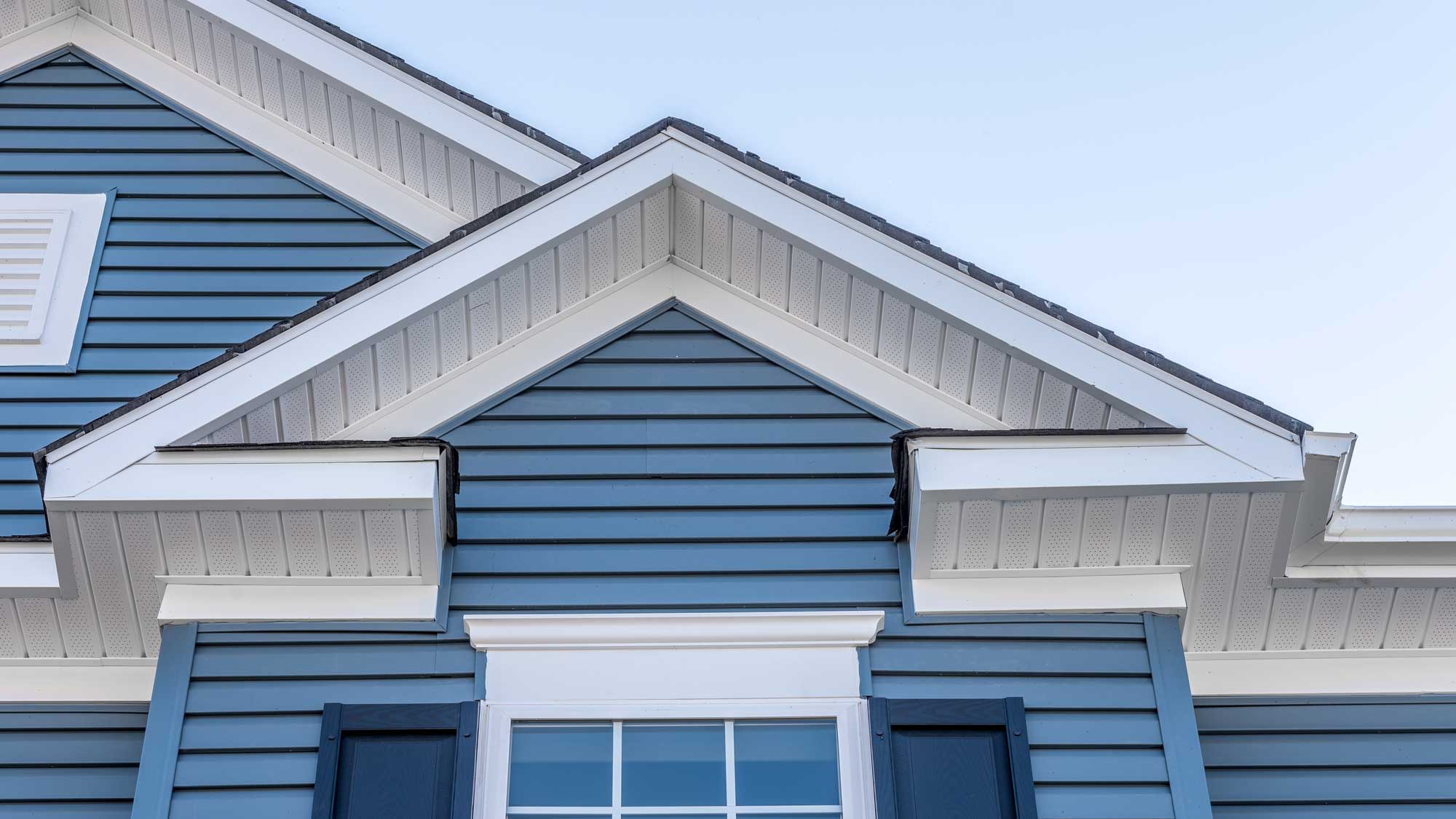 Closeup of the top floor of a home with blue vinyl siding
