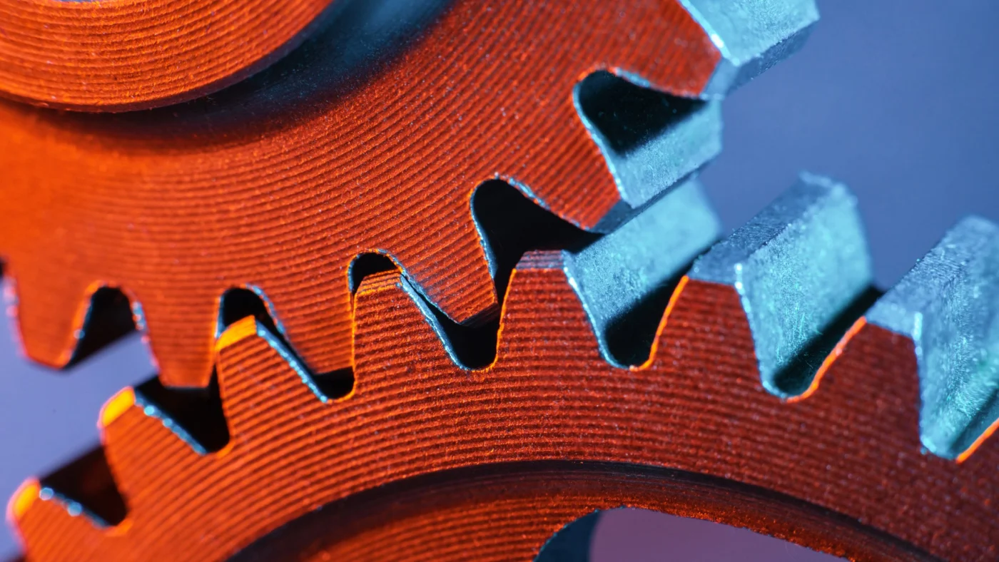 Close-up of interlocking metal gears, symbolizing one team working together to keep every part of a home remodeling project moving smoothly.